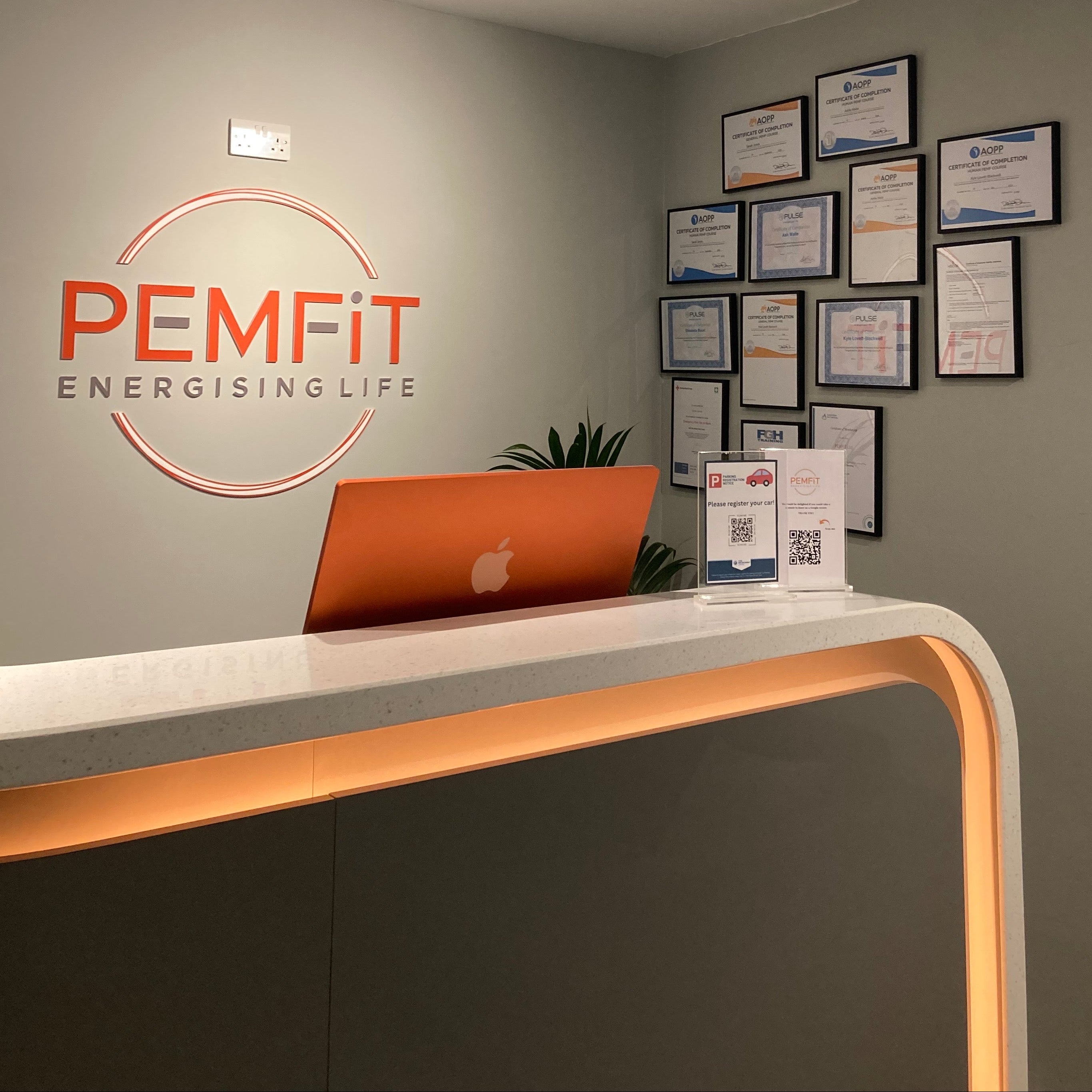Office interior with PEMFIT logo on the wall and framed certificates on the wall.