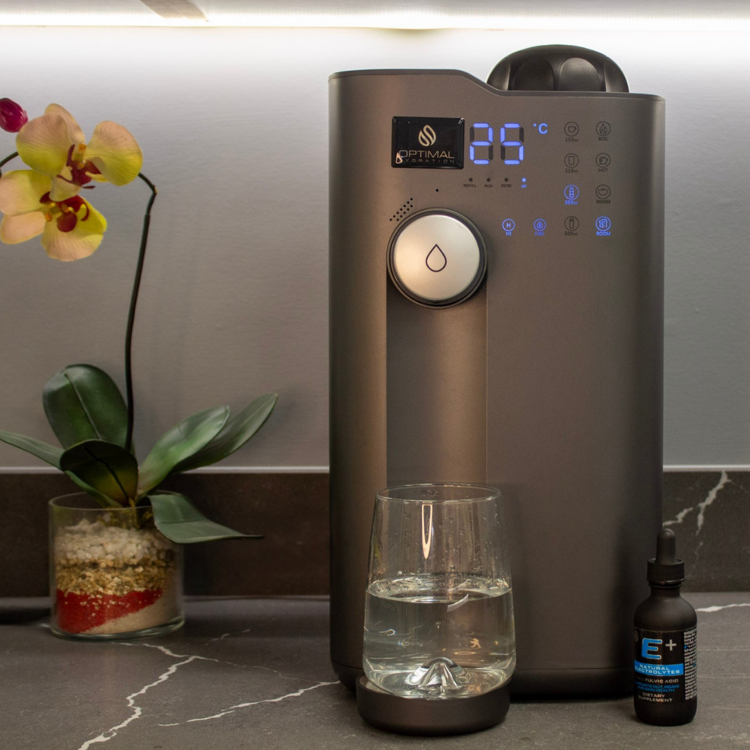Modern water purification dispenser on a kitchen counter with a glass of water and E+ Natural Electrolytes nearby.